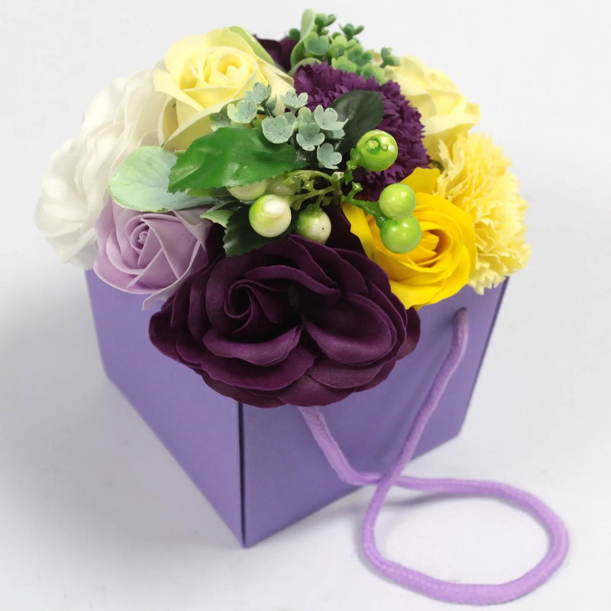 Bouquet de flores de jabón en tonos morados, amarillos y blancos, presentado en una caja de regalo morada con asa