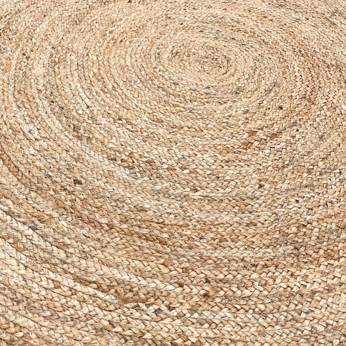 Alfombra redonda artesanal de yute y algodón reciclado en tonos beige con textura trenzada en espiral.