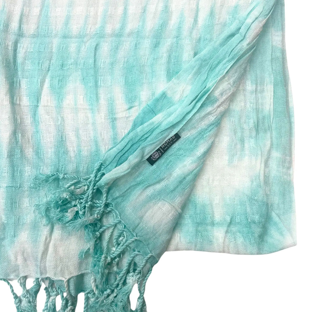 Estola bohemia de lino y rayón con rayas tie-dye turquesa y blancas, textura de cuadros y flecos en los extremos.