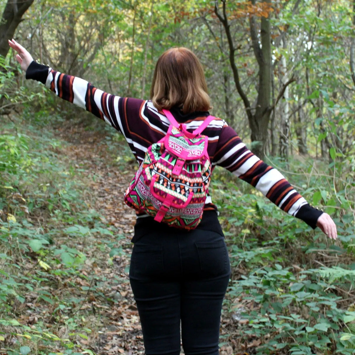 Mochila de estilo nepalí en tejido jacquard rosa y geométrico sobre una persona en un bosque.