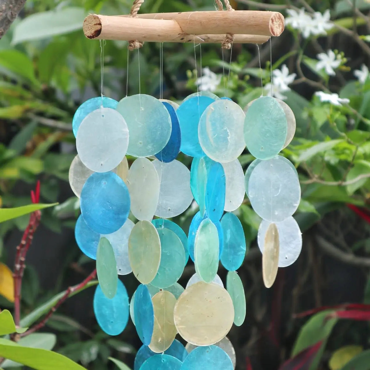 Carillón decorativo con discos circulares de nácar en tonos azules y perla, colgados de una estructura de madera natural.