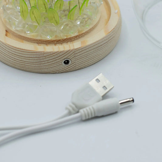 Domo de jardín con tulipanes sobre base de madera clara, piedras decorativas y cable de alimentación USB incluido.