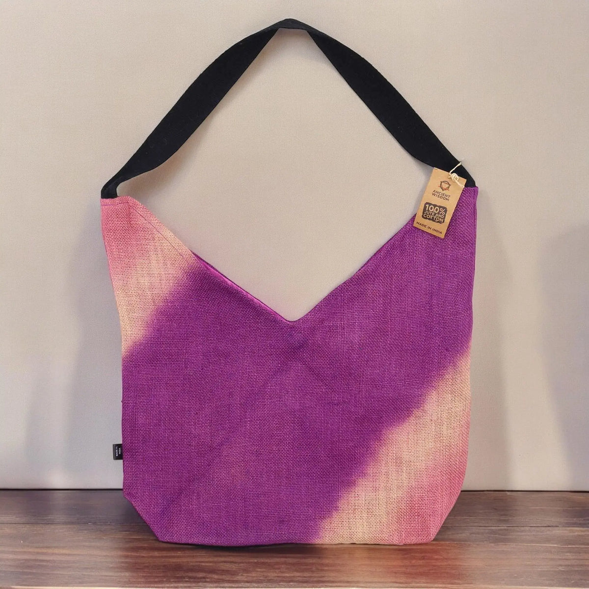 Bolso de hombro estilo vintage en fucsia y crema, de tela con textura natural y asa larga negra sobre fondo neutro.