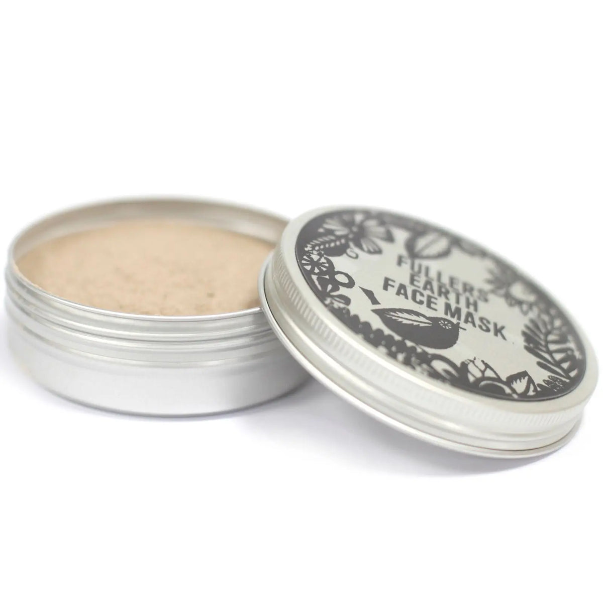 Tarro metálico abierto con mascarilla de arcilla beige y tapa decorada con motivos botánicos y texto en negro.