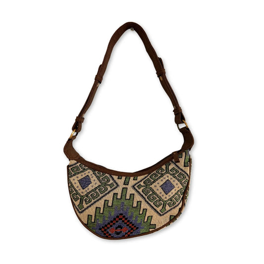 Bolso hobo semicircular de jacquard con diseño geométrico en verde, azul y beige, y correa ajustable de cuero marrón.