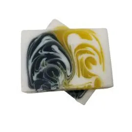Dos pastillas de jabón artesanal rectangular con diseño marmolado en tonos amarillo, negro y blanco sobre fondo blanco.