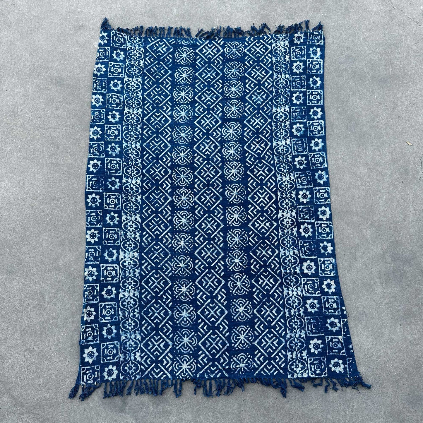 Manta de algodón azul marino con diseño geométrico, fringes en los bordes, ideal para decoración.