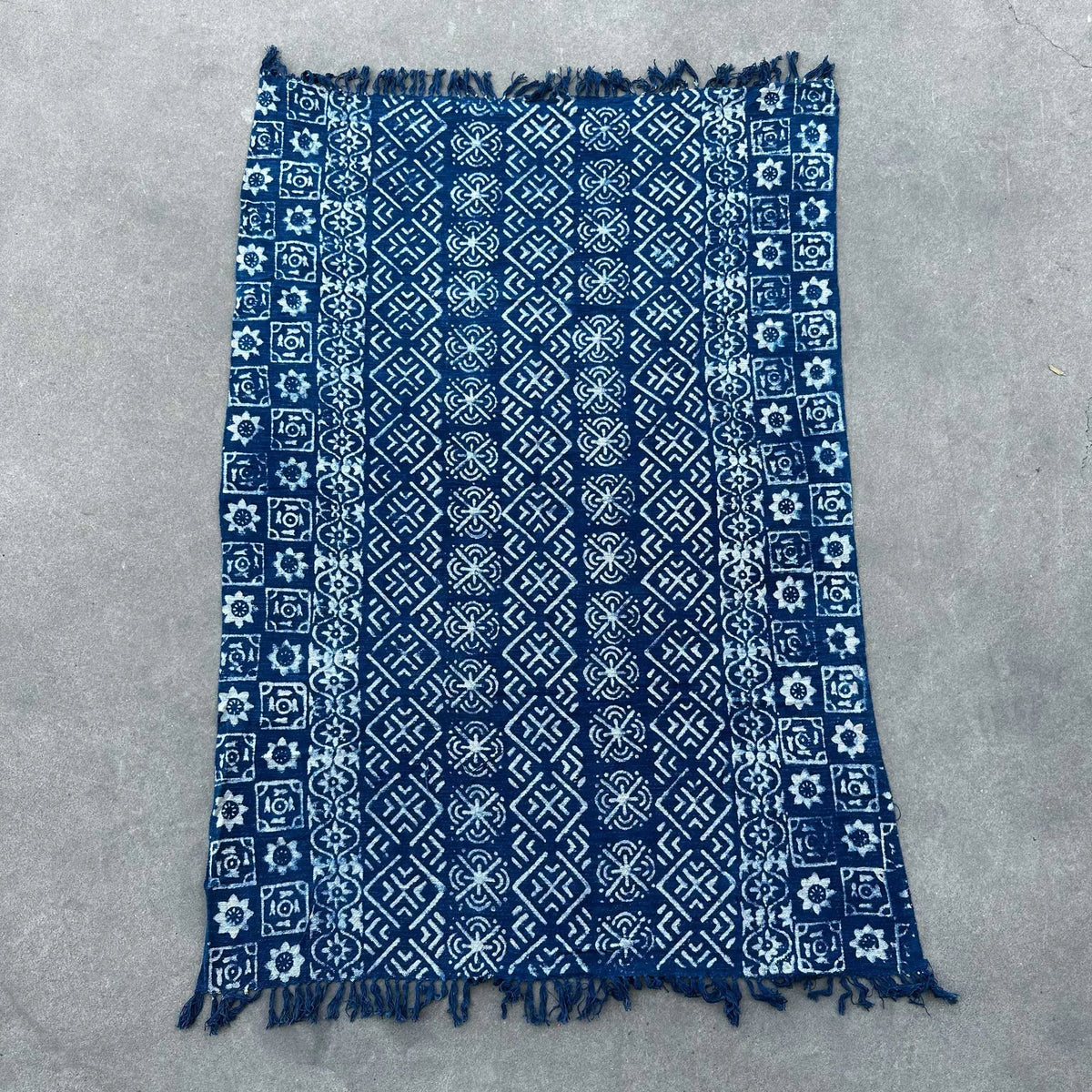 Manta de algodón azul marino con diseño geométrico, fringes en los bordes, ideal para decoración.