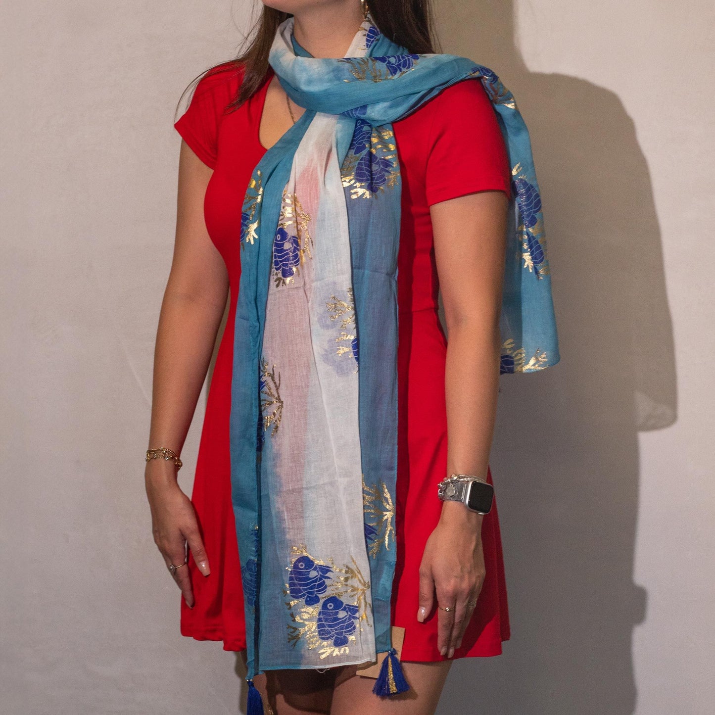 Bufanda azul con dorado, de material liviano y estilizada, combinada con vestido rojo. Ideal para ocasiones casuales.