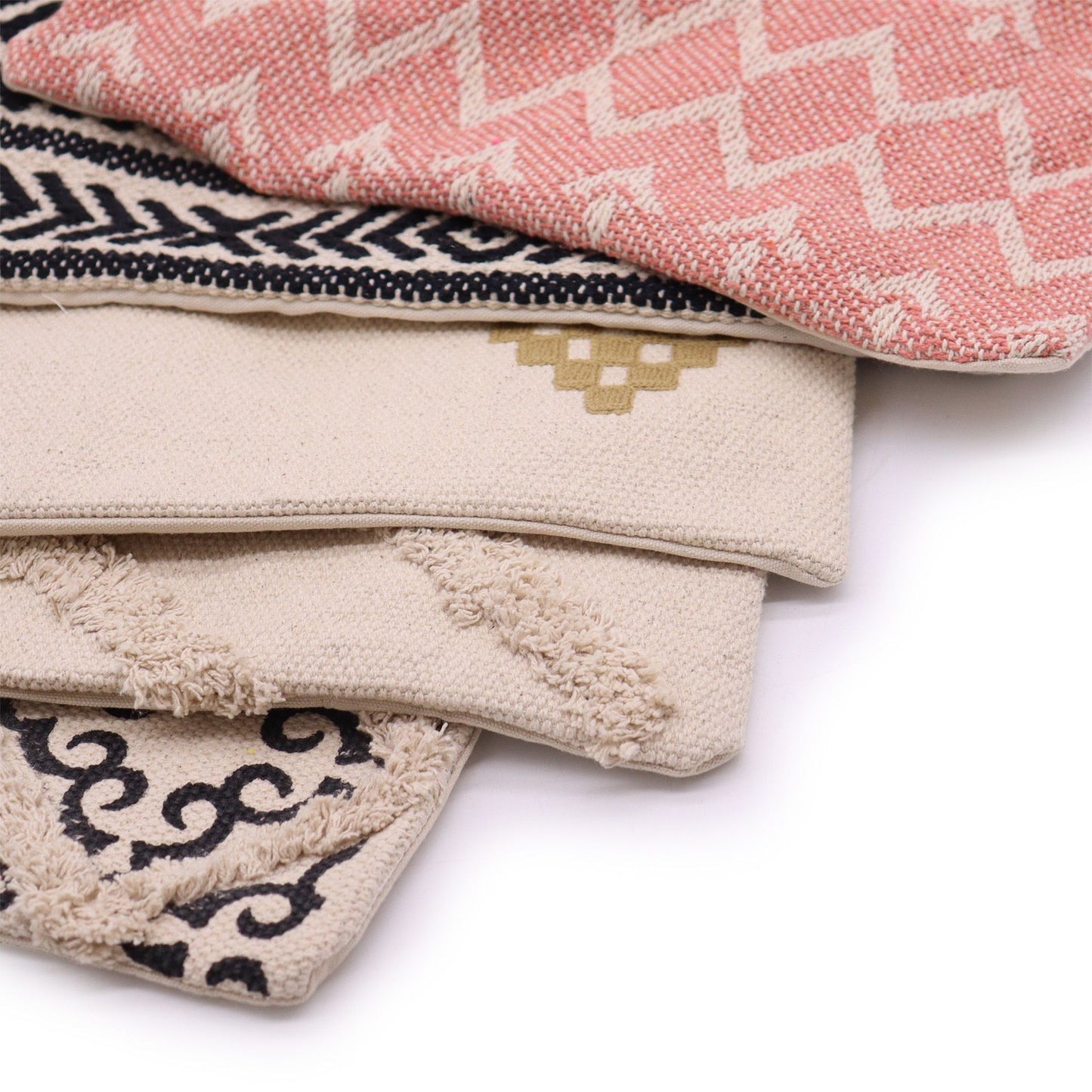 Fundas de cojín de 45x45cm con diseños tribales y geométricos en tonos beige, negro y rosa, de tela texturizada.