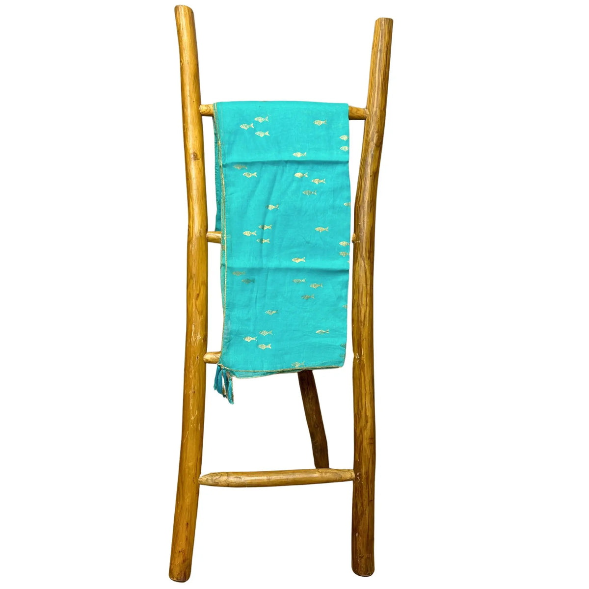 Pareo turquesa con estampado de peces dorados colgado sobre una escalera decorativa de madera natural.