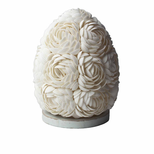 Lámpara boho ovalada de 15cm hecha a mano con pequeñas conchas blancas dispuestas en forma de flores sobre una base.