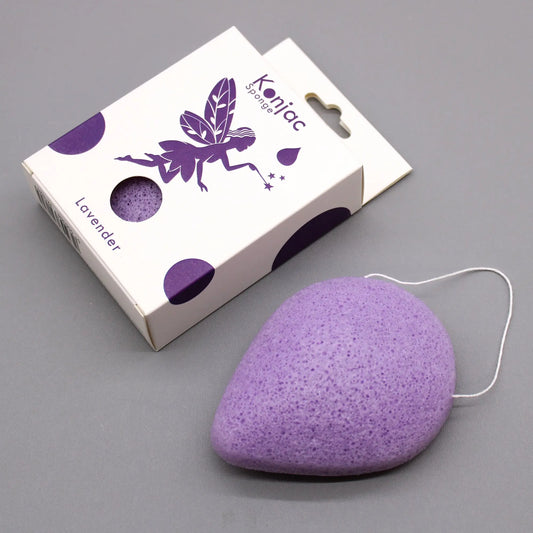Esponja facial Konjac de color morado con forma de gota y cordón, junto a su caja de empaque con diseño de hada.