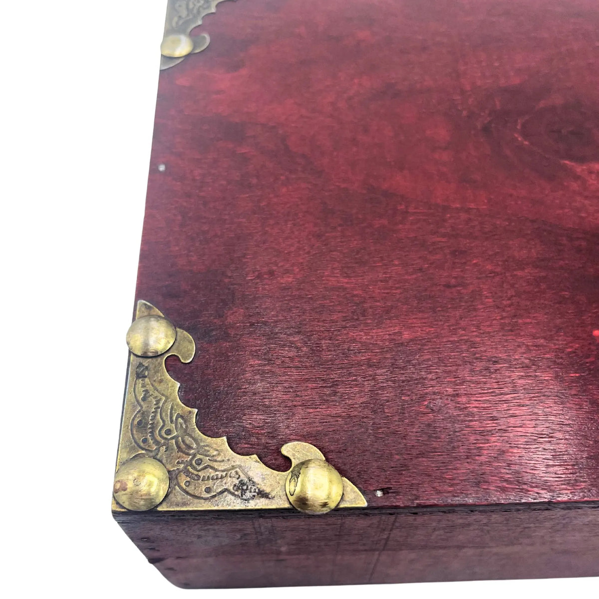 Caja de madera color granate con esquinas metálicas de latón repujado, estilo vintage, fondo blanco.