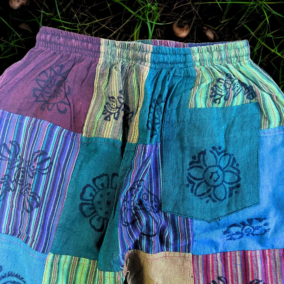 Pantalón estilo nómada, patchwork en tonos verdes, morados y azules, con estampado floral y cintura elástica.