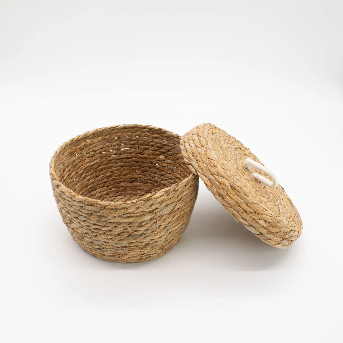 Cesta redonda de hierba marina trenzada color natural con tapa y asa de algodón, estilo artesanal y orgánico.
