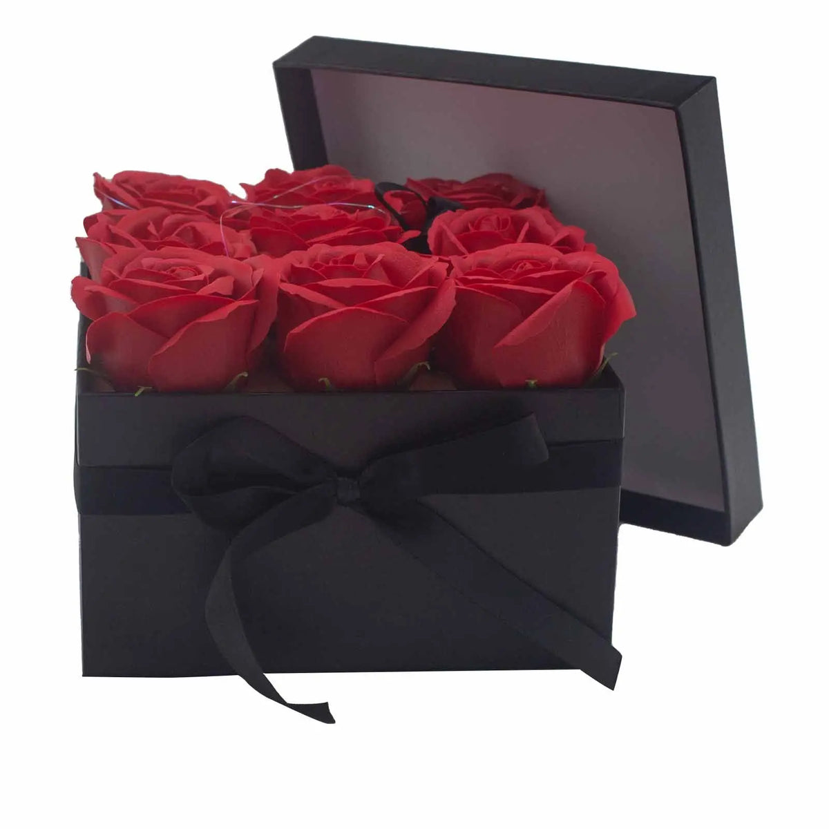 Caja negra cuadrada con lazo decorativo que contiene nueve rosas rojas de jabón realistas.