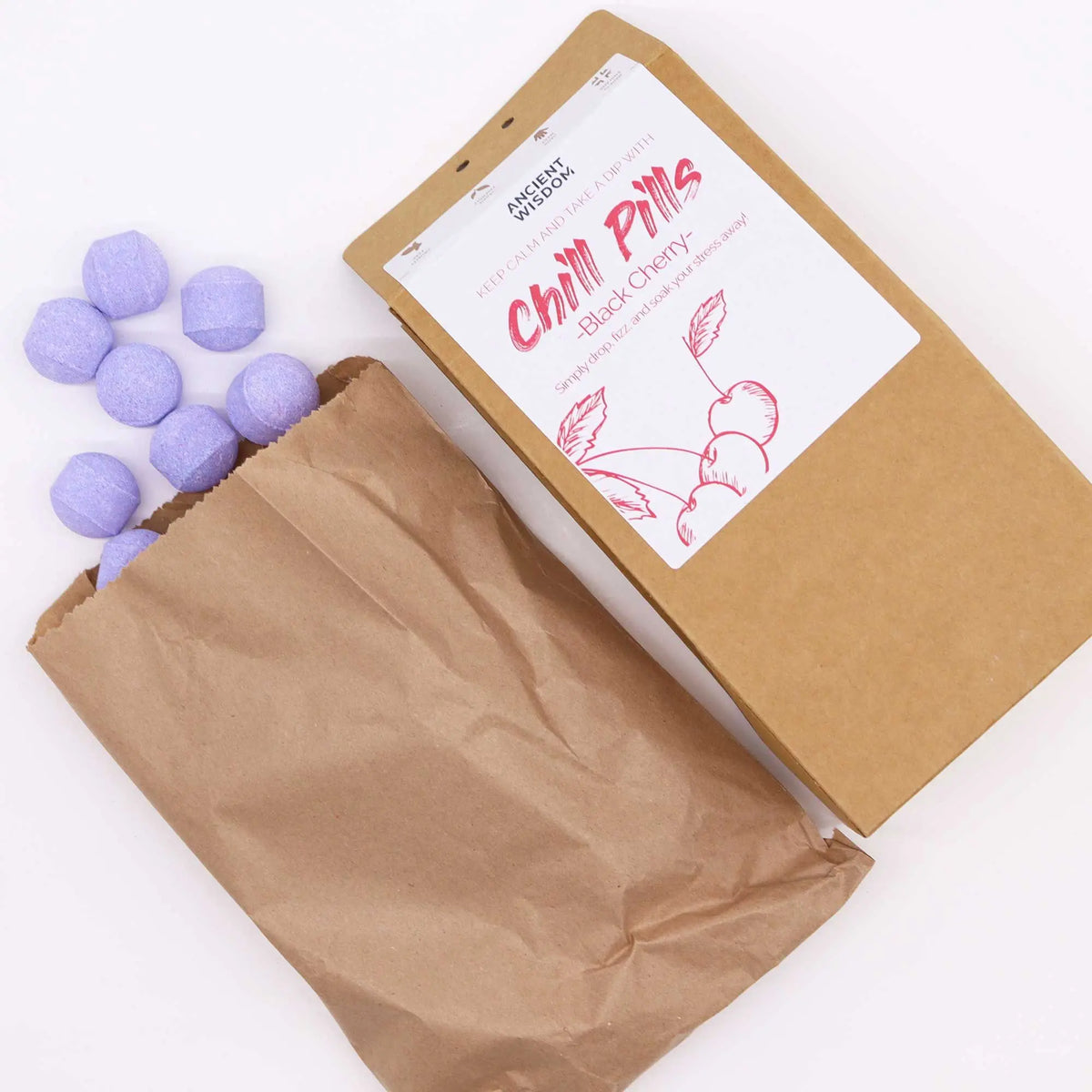 Bolsa de papel kraft con mini bombas de baño efervescentes de color violeta claro y aroma a cereza negra.
