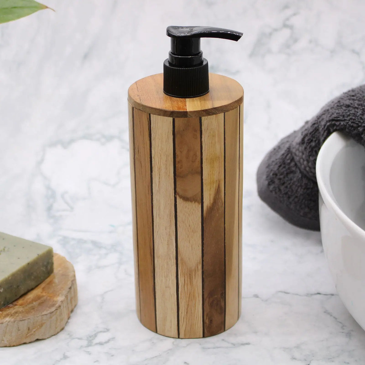 Dispensador cilíndrico de jabón líquido hecho de láminas de madera natural con dispensador superior de plástico negro.