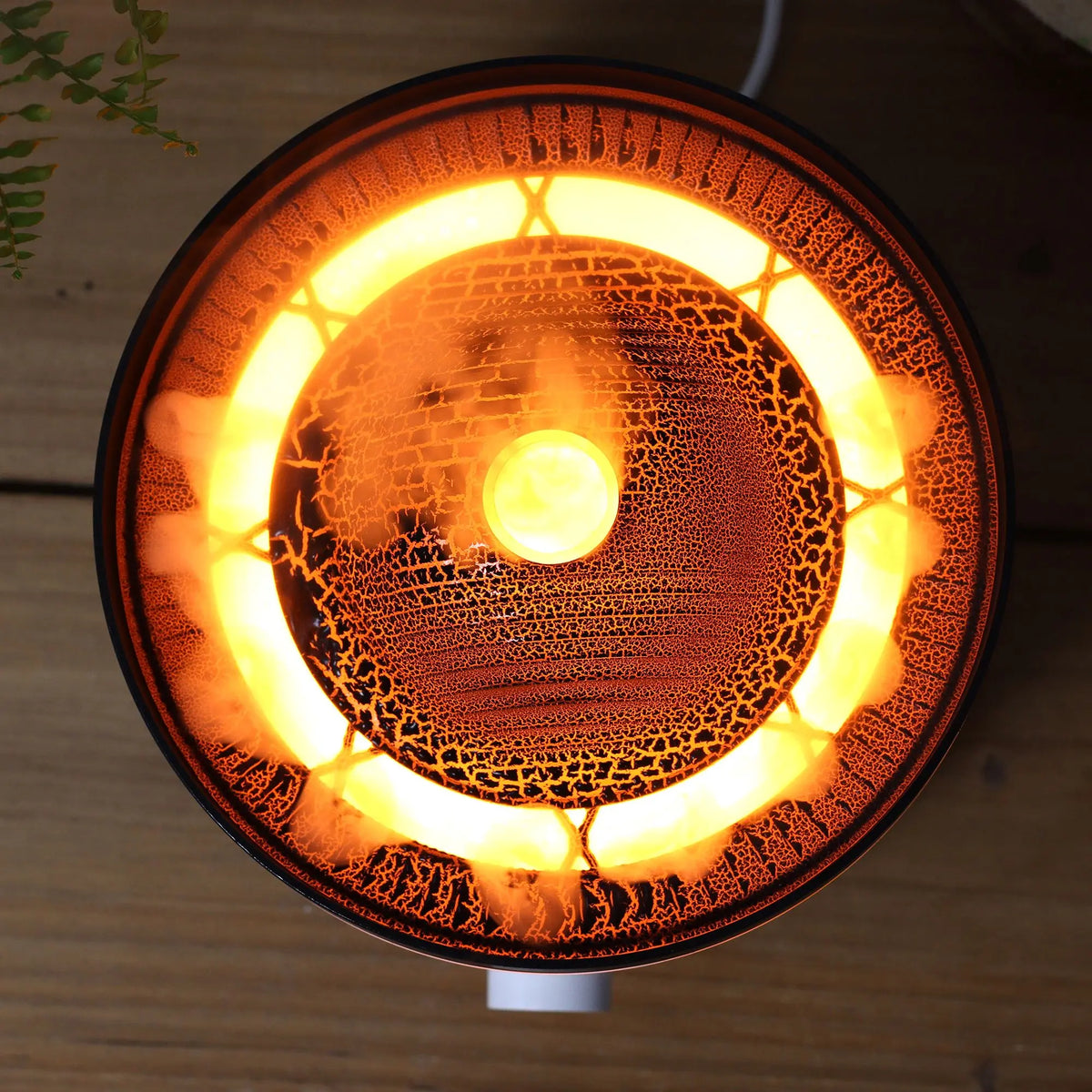 Difusor eléctrico Ancient Wisdom con diseño circular, texturas oscuras y luz cálida central efecto volcán incandescente.