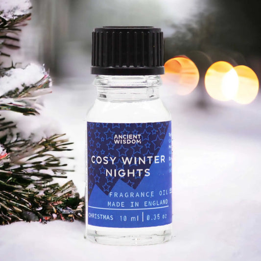 Frasco de vidrio de 10ml con etiqueta azul de estrellas sobre nieve, junto a un árbol de Navidad con luces desenfocadas.