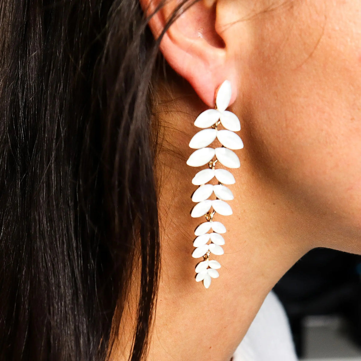 Pendientes largos colgantes con forma de rama y hojas de perla blanca sobre base metálica dorada.