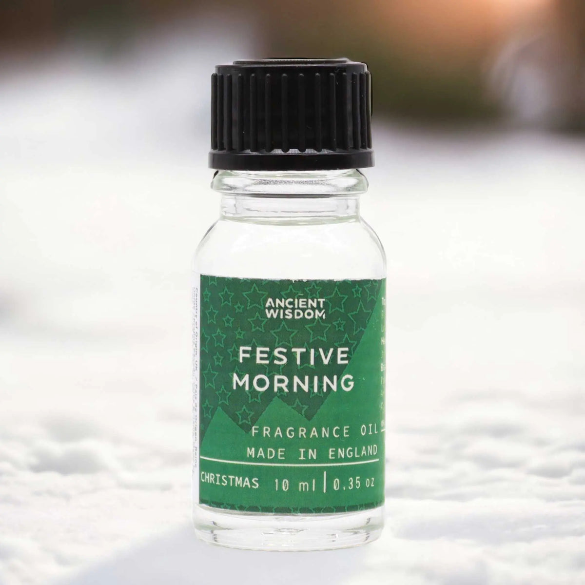 Frasco de vidrio de 10 ml con tapón negro y etiqueta verde con estrellas blancas sobre fondo nevado.