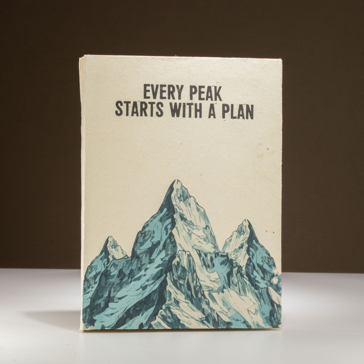 Cuaderno artesanal con portada de montaña en tonos azules y beige, estilo minimalista y motivacional.