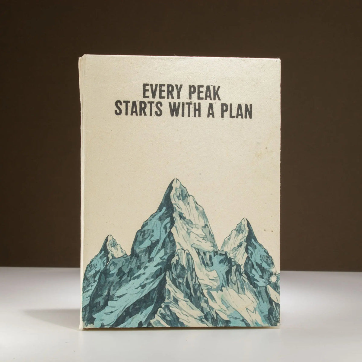 Cuaderno artesanal con portada de montaña en tonos azules y beige, estilo minimalista y motivacional.