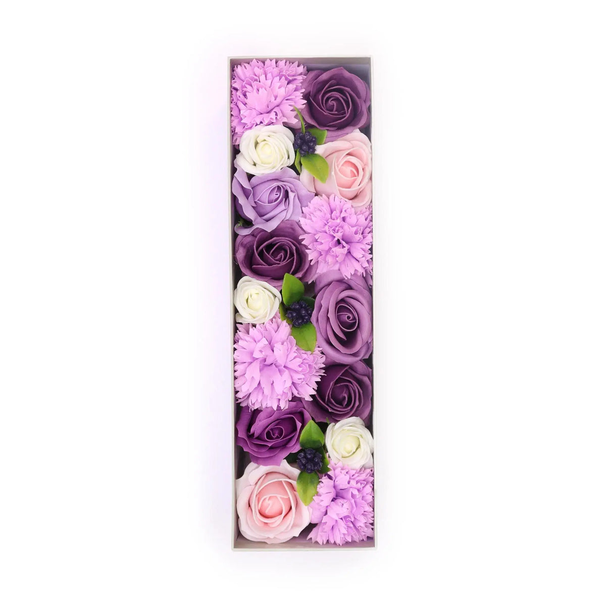 Caja rectangular con rosas y claveles de jabón en tonos lavanda, violeta, rosa y blanco con hojas verdes decorativas.