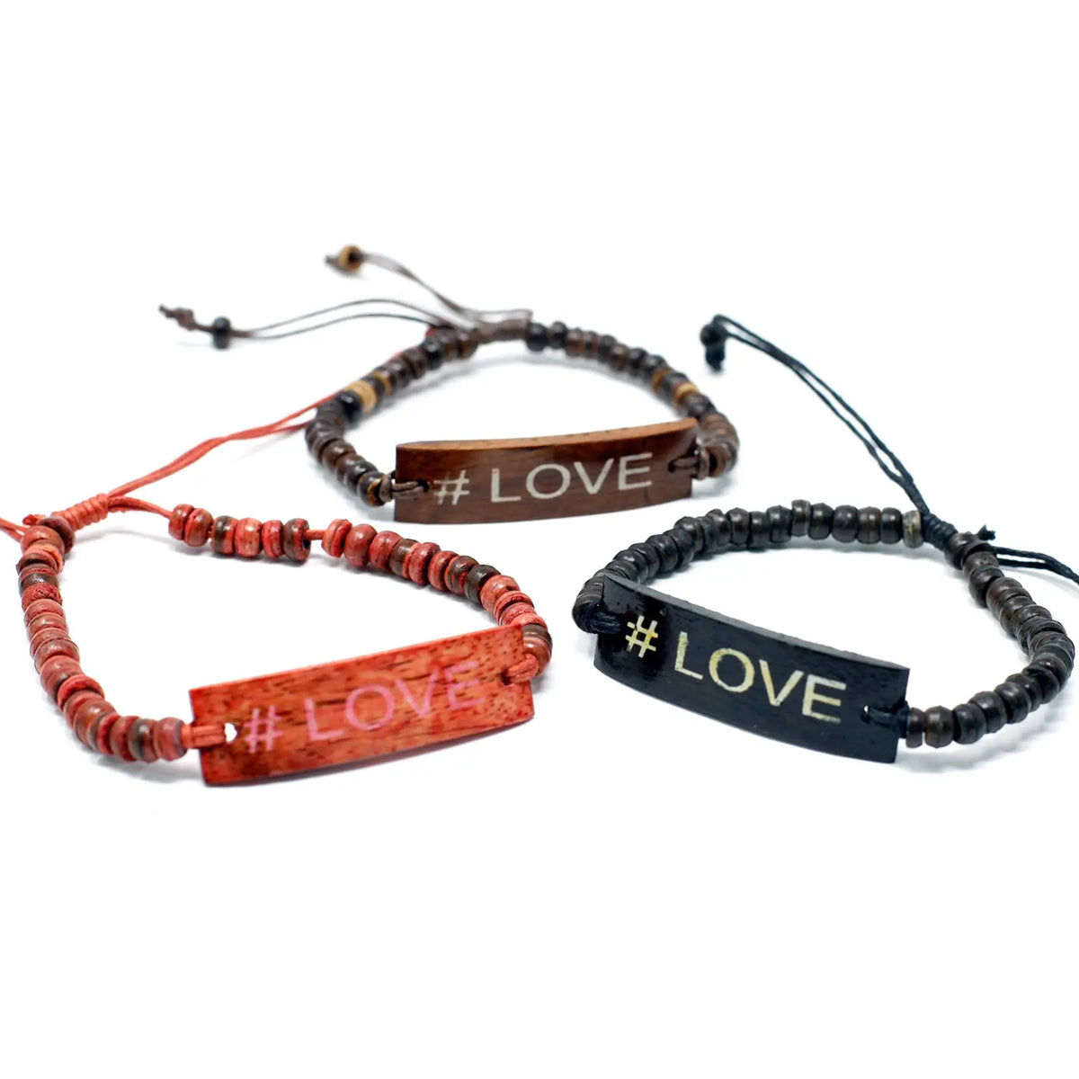 Tres pulseras artesanales de cuentas de madera de coco con una placa central grabada con el mensaje #LOVE.