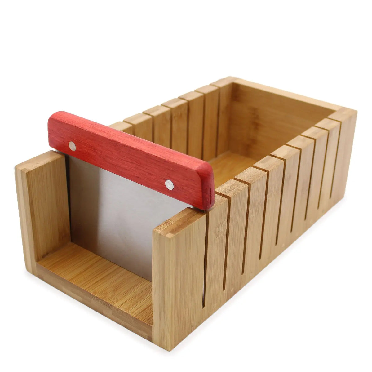 Cortador de jabón de madera tipo caja con ranuras y cuchilla metálica con mango de madera roja. Fondo blanco.