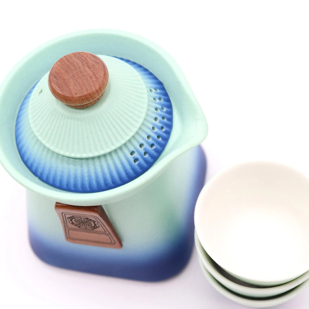 Juego de té cerámico azul degradado con tetera de tapa estriada, pomo de madera y tres tazas apiladas.