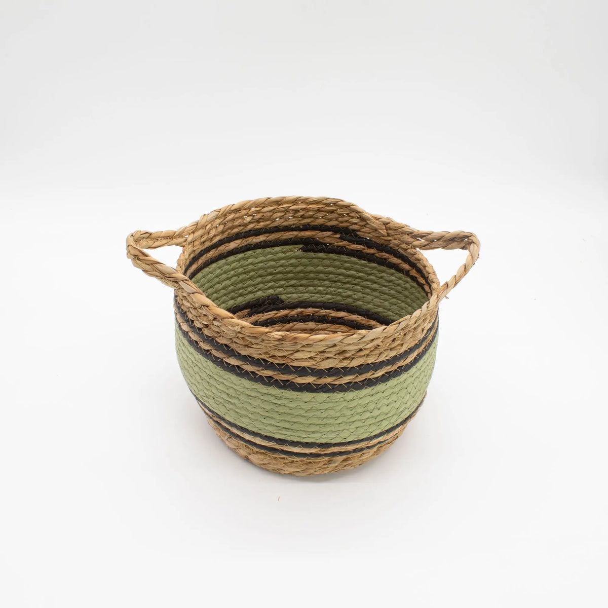 Cesta artesanal de pasto marino y algodón en tonos natural, verde y negro, con dos asas laterales sobre fondo blanco.