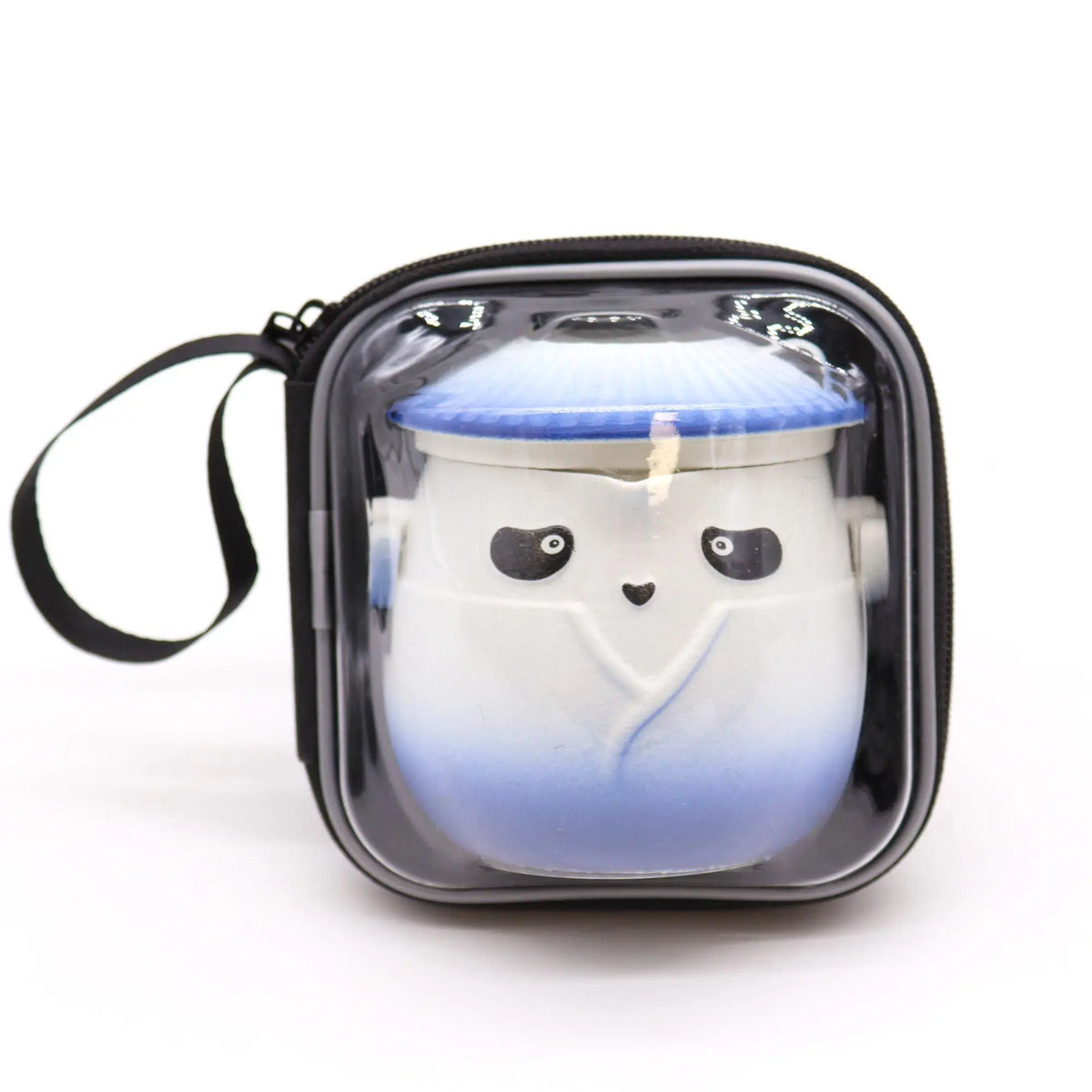 Tetera de cerámica con forma de panda en azul y blanco, guardada en un estuche de transporte con ventana transparente.