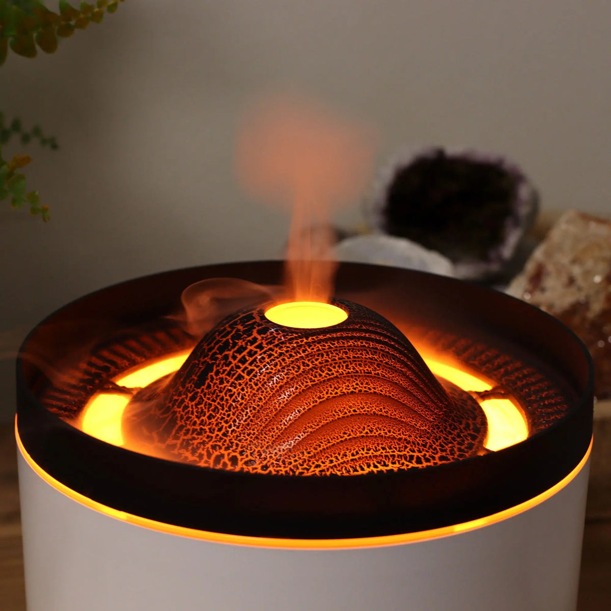 Difusor eléctrico de aromaterapia con diseño de volcán, luz LED cálida y vapor que simula una erupción en color negro.
