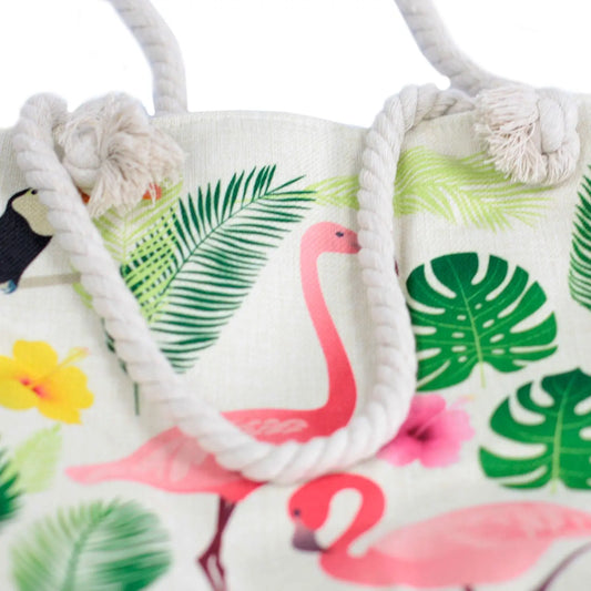 Bolso shopper de tela con estampado tropical de flamencos, flores y hojas, con asas de cuerda trenzada en color beige.