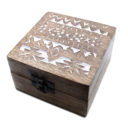 Caja cuadrada de madera oscura con cierre metálico y tallados decorativos en blanco con diseño geométrico.
