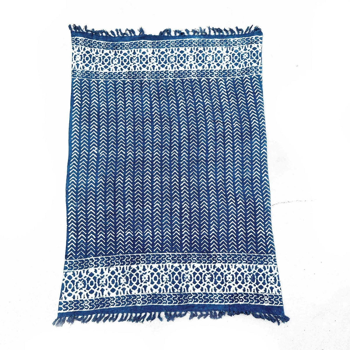 Alfombra azul marino con diseño geométrico y bordes blancos. Tejida de algodón con flecos. Ideal para decoraciones modernas.