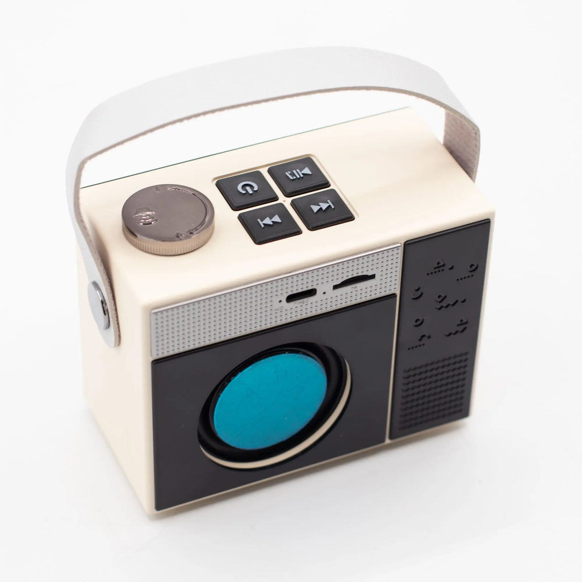 Altavoz Bluetooth retro color crema y negro, con asa, dial giratorio y controles superiores sobre fondo blanco.