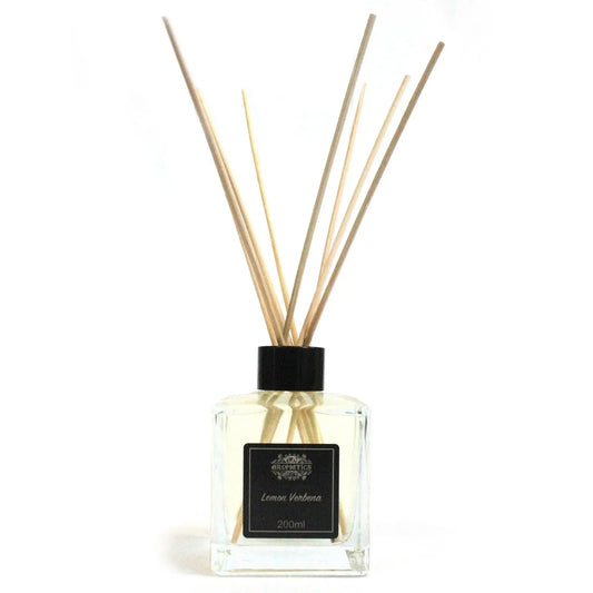 Difusor de varillas con frasco de cristal cuadrado transparente, tapón negro y etiquetas minimalistas sobre fondo blanco