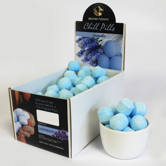 Caja con mini bombas de baño efervescentes color azul claro con aroma a lavanda y un recipiente lleno frente a ella.
