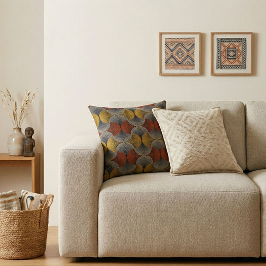 Cojines de algodón con patrones en tonos rojo, amarillo y gris sobre sofá beige en salón moderno.