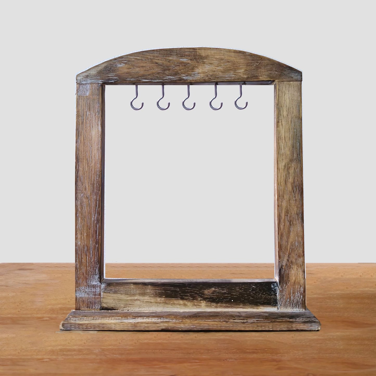 Soporte artesanal de madera oscura con marco arqueado y cinco ganchos metálicos para colgar accesorios. 30x25 cm.