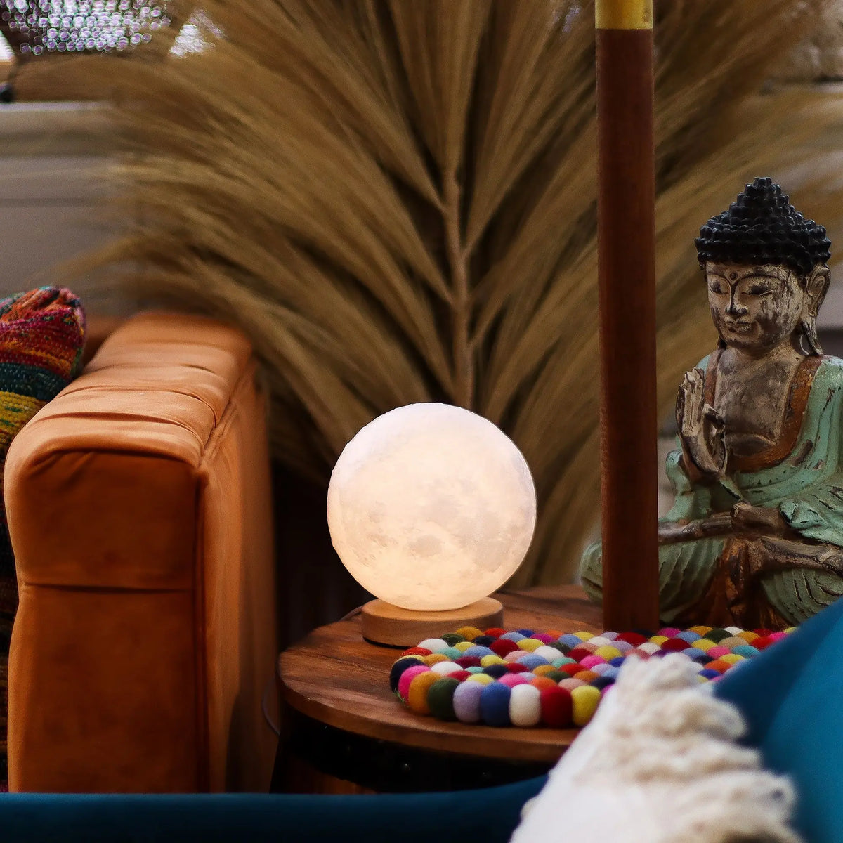 Lámpara esférica tipo luna sobre base de madera, con luz ambiental cálida, situada sobre una mesa auxiliar de madera.