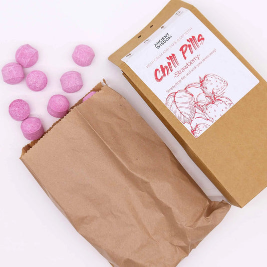 Mini bombas de baño rosas con aroma a fresa saliendo de una bolsa de papel kraft con etiqueta ilustrada.