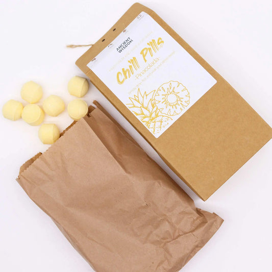 Bolsa de papel kraft con mini bombas de baño efervescentes amarillas con aroma a piña colada y etiqueta ilustrada.
