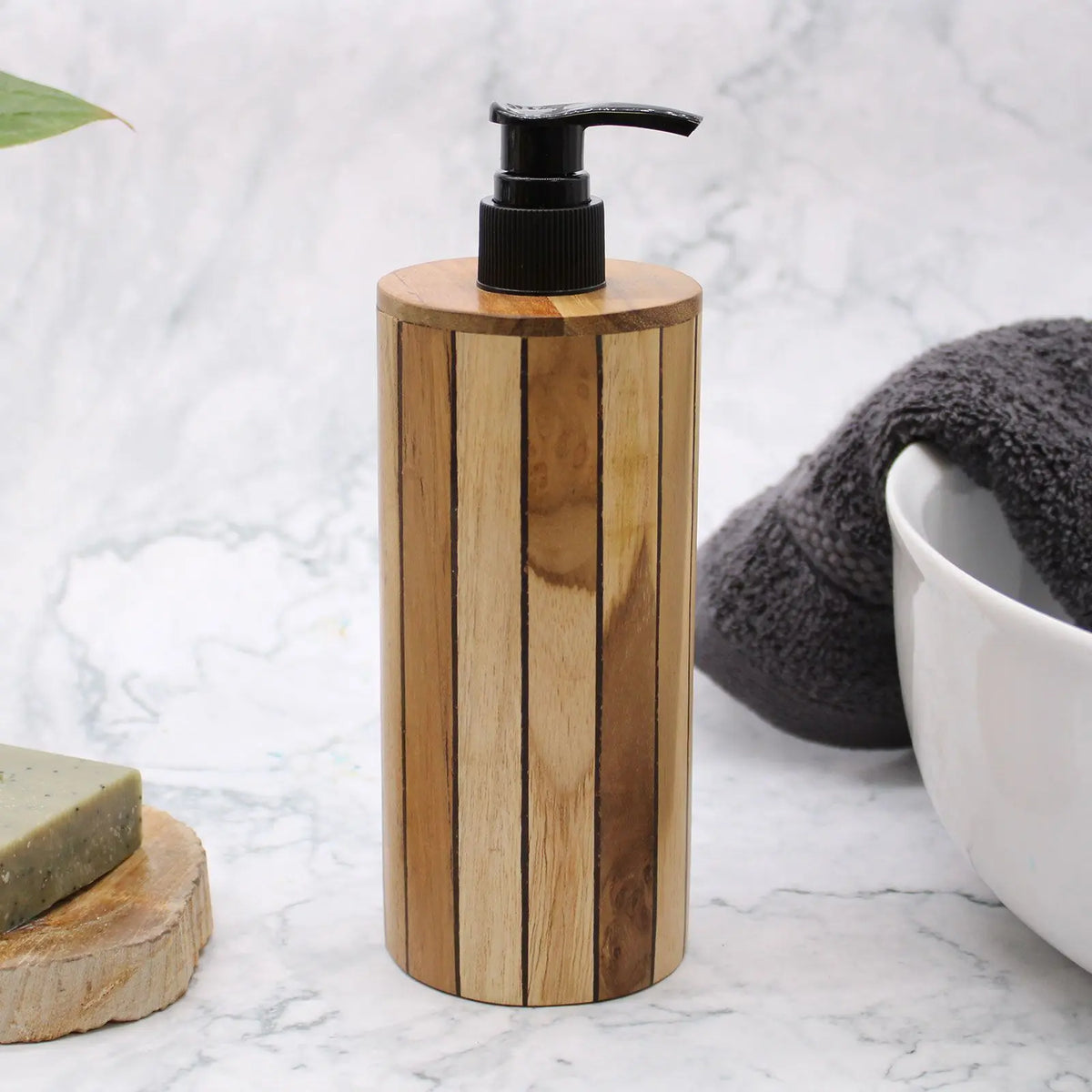 Dispensador de jabón cilíndrico de madera natural con vetas rayadas y dosificador de bomba negro sobre fondo de mármol.