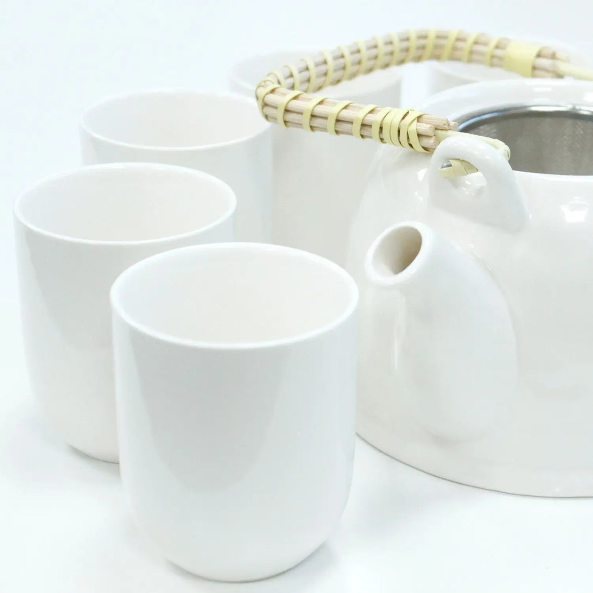 Set de té Ancient Wisdom: tetera blanca de cerámica con asa de bambú y tazas a juego sobre fondo blanco.