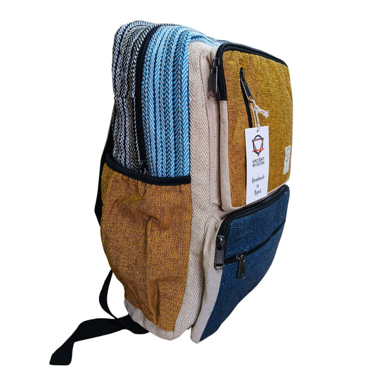 Mochila de cáñamo con paneles de colores cúrcuma, azul y beige, diseño artesanal, varios bolsillos y cierres de cremallera.